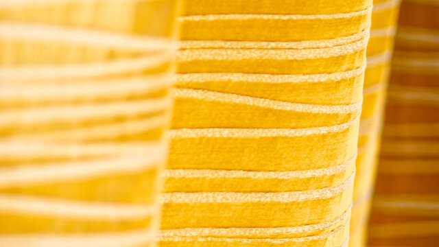 Close-up of custom-made golden striped curtains from premium manufacturer Zimmer & Rohde with elegant horizontal stripe pattern in warm gold tones in furnished apartment Bamberg