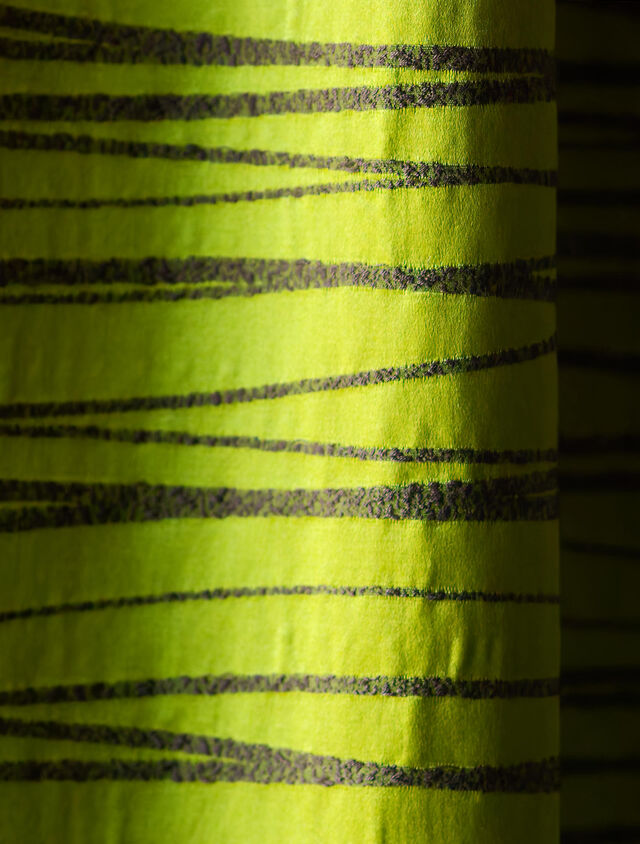 Close-up of custom blackout curtains with horizontal black stripes on metallic green background for effective room darkening and restful sleep in bedroom of furnished apartment Bamberg