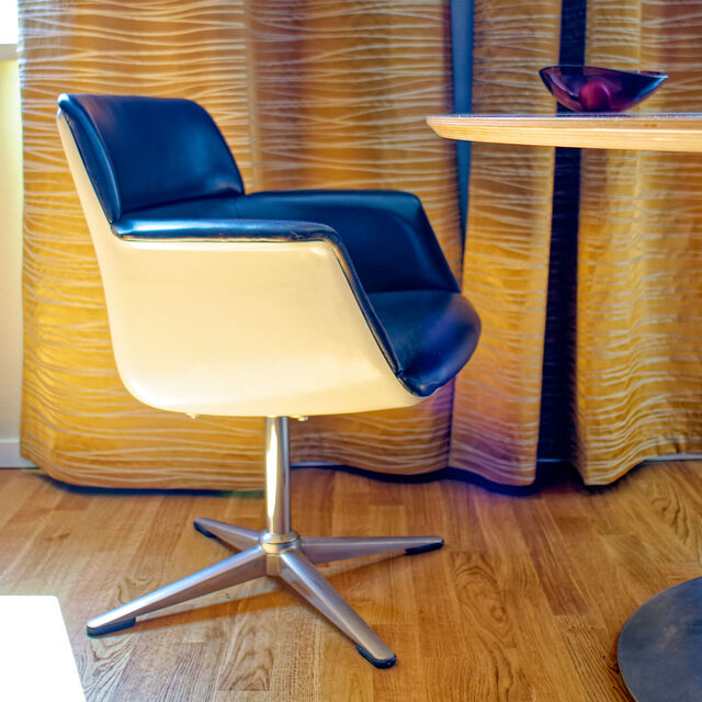 Friso Kramer vintage designer swivel chair with black artificial leather and chrome base in front of golden curtains in furnished apartment Bamberg