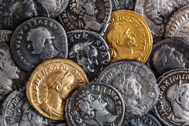 Ancient Roman coins in gold and silver scattered together, representing historical currency and pricing through the ages.
