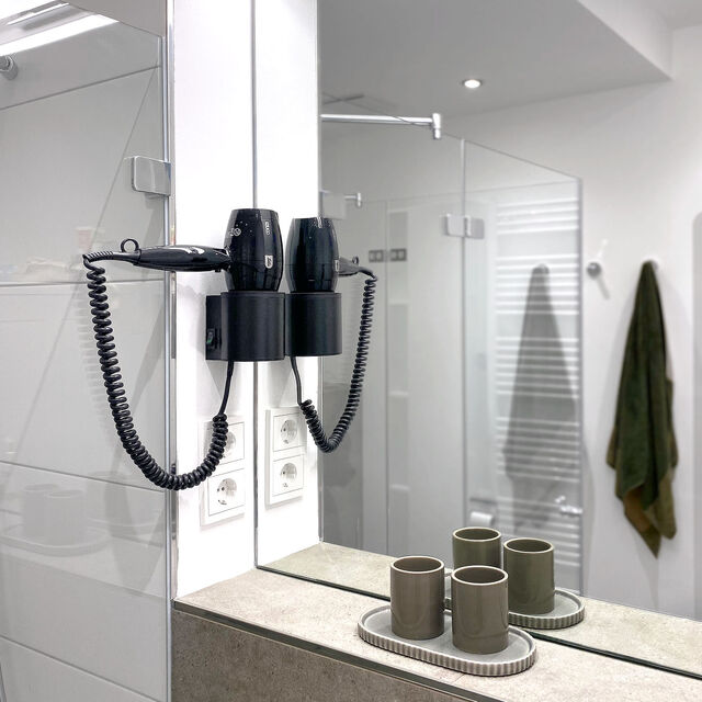 Modern bathroom mirror with LED lighting, wall-mounted hairdryer and elegant ceramic bathroom accessories in furnished apartment Bamberg